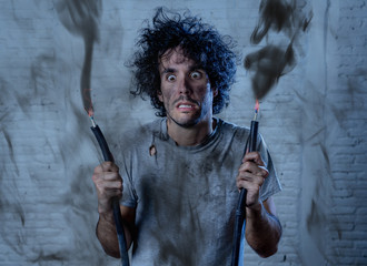 Funny image of man holding electrical cable after getting electric shock