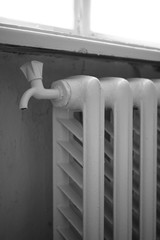 Old cast iron radiator with faucet, central heating indoors.