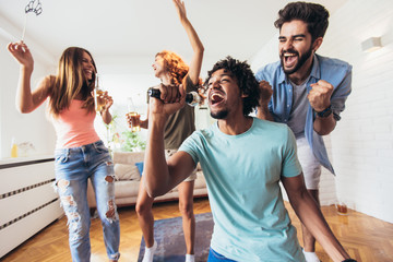Group of friends playing karaoke at home.Group of friends having party together at home.