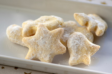 whipped cream delicious cookies with sugar icing on white ceramic plate, tablecloth with golden stars
