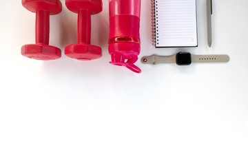 Do fintess in gym. Dumbbells, smart watch, bottle of water, blank notebook on white background top view space for text pattern.