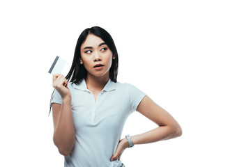 Fototapeta premium dreamy asian girl holding credit card and looking away isolated on white
