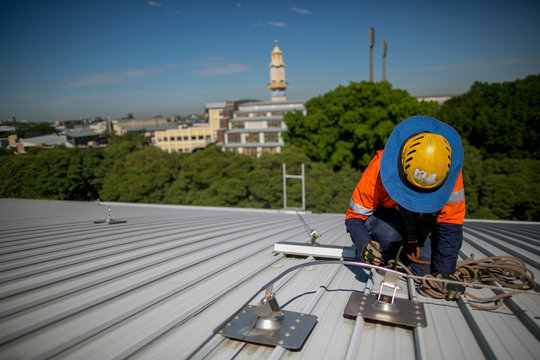 Certifies Industry Inspector Worker, Wearing Safety Fall Protection Hard Hat Conducting Inspection Services On Full Arrest Anchor Point Roof Safety Line, Writing Up To Date Information On Data Plate 