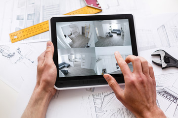 Close-up Of A Person's Hand Monitoring CCTV Footage On Digital Tablet