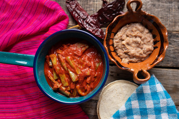 Mexican nopal cactus with guajillo red sauce on wooden background