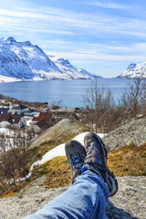 A man, sitting on a rock, enjoying the view of Ersfjord in winter, Ersfjordbotn, Troms, Norway
