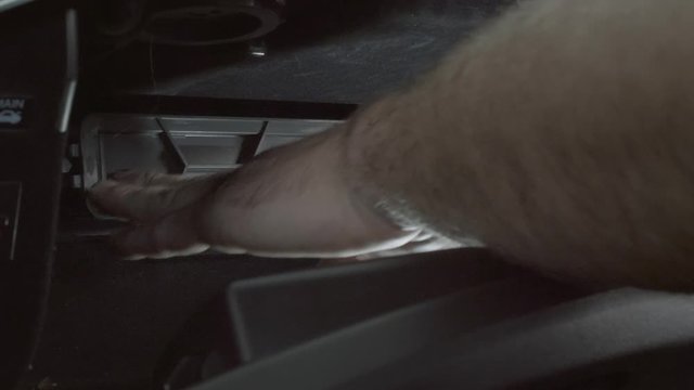 A professional mechanic replaces the cabin air filter and housing in a car. Close up detail of mans hands as he works.