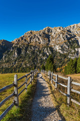 Fototapeta na wymiar road with wooden fence in the mountains, dolomite alps, south tyrol