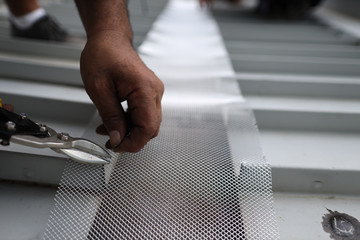 Safety workplace handy repairing man repairing roof wire mesh grid using cutter cutting with plier...