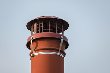 Isolated view of an old fashioned, terracotta chimney pot seen on a cottage roof, against a clear...