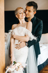 The newlyweds hugging in the hotel room. Vintage wedding style
