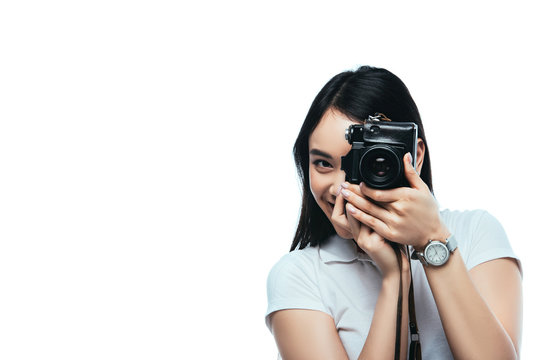 smiling brunette asian woman taking picture on digital camera isolated on white