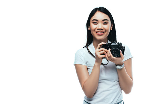 smiling brunette asian woman taking picture on digital camera isolated on white