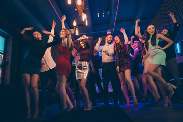 Low angle view photo of positive cheerful crowd people gathering have noel holidays want party hard go discotheque dance floor raise hands scream feel crazy like wild youth