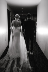 Black and white photo of wedding couple walking down the hall