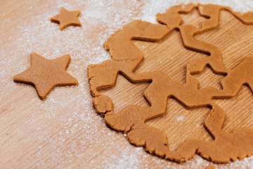  Dough for gingerbread cookies on a table sprinkled with flour. Cutting cookies in the shape of stars.
