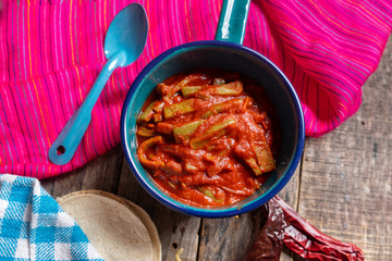 Mexican nopal cactus with guajillo red sauce on wooden background