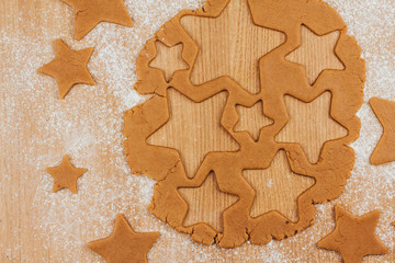 Dough for gingerbread cookies on a table sprinkled with flour. Cutting cookies in the shape of stars.