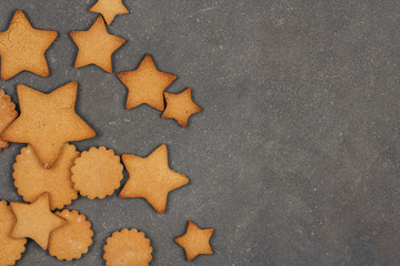 Gingerbread cookie in the shape of stars and circles on a dark gray background with space for text. 