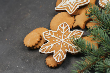  Gingerbread cookie in the shape of stars, circles and snowflakes on a dark gray background. Christmas cookies with icing decor.