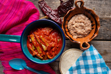 Mexican nopal cactus with guajillo red sauce on wooden background