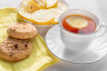 Tea in a white Cup with lemon and biscuits