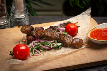 lamb skewers with pickled onions and cilantro on a wooden board and ketchup in a cup