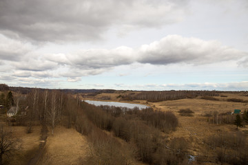 Fototapeta na wymiar Panorama of the spring landscape with a lake and hills with copses. Izborsk, Pskov region, Russia.