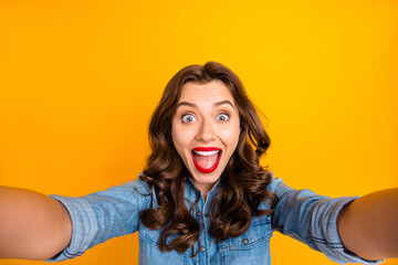 Photo of curly wavy trendy cheerful excited brunette haired girl overjoyed with being able to shoot photos and videos taking selfie showing her positive emotions isolated over vivid color background
