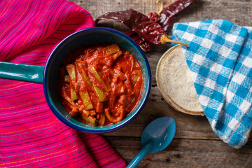 Mexican nopal cactus with guajillo red sauce on wooden background
