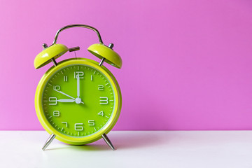 Alarm green vintage alarm clock falling on the floor with pink color background. Morning and Start up Concept