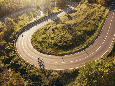 aerial view on two cyclists on a windy mountainroad in upper franconia at sunset