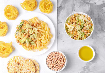 Vegetarian cuisine. Salad with chickpeas and cabbage, pasta, olive oil, crisp bread. Concrete background