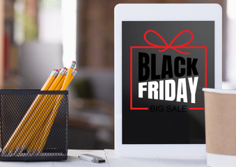 Front view of tablet and office accessories with black friday lettering on blurred background. Copyspace for your advertising. Black friday, sales, finance, advertising, money, finance, purchases.