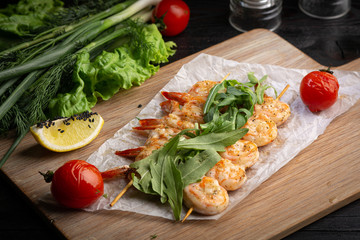 shrimp skewers on a skewer with arugula, baked tomato and lemon