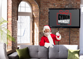 Front view of Santa pointing of screen with cyber monday lettering in modern home or office....