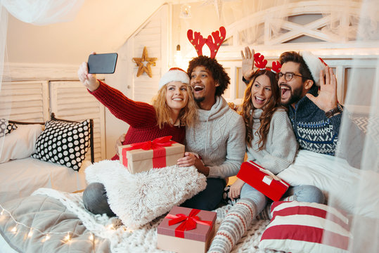 Friends sitting on a large bed, taking a selfie; enjoying, happy, smiling 