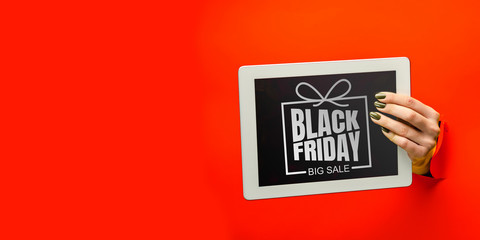 Hands holding tablet screen with black friday lettering on red background. Concept of sales, black friday, cyber monday, finance, business, money. Online shops and payments bill.