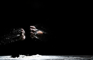 Chef hand clap and white flour on black background