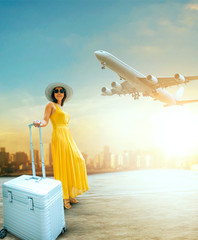 beautiful woman and traveling luggage standing in airport terminal with passenger plane flying over...