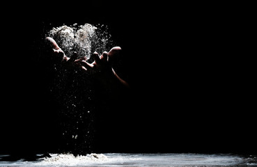 Chef hand clap and white flour on black background