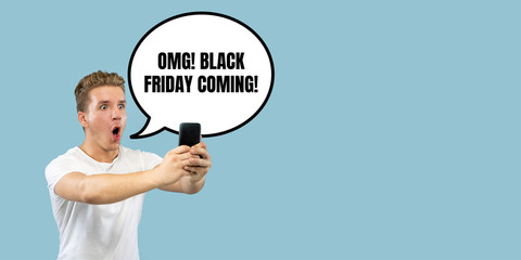 Half-length close up portrait of young man on blue background. The human emotions, black friday, cyber monday, purchases, sales, finance concept. Trendy colors. Negative space. Shocked, astonished