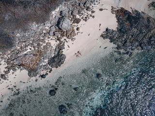 Loving couple lying on the sand at the picturesque seashore, drone shot. Happy couple concept