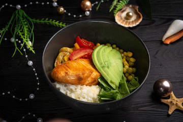 bowl with salmon in a black plate on a dark wooden background