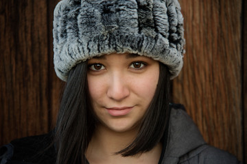 Closeup of Beautiful Young Woman Wearing Gray Fur Hat and Looking at Camera