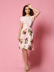 Cute slender girl in red dress for a date - a blouse and a fluffy skirt posing in the studio on a pink background. to meet spring and summer. Wardrobe update