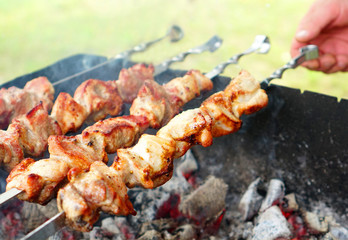 Roasting meat on skewers on the grill in the fresh air in sunny weather