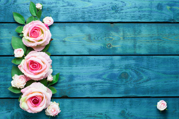 Wedding border with pink rose flowers on blue wooden background