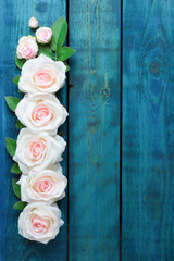 Wedding border with one row of light pink rose flowers on blue wooden background