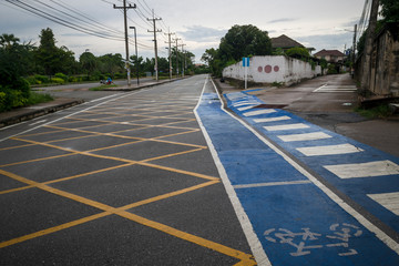 Concrete road with intersections to the left and right There is a way for bicycles, there is a blue road surface and framed with white lines.